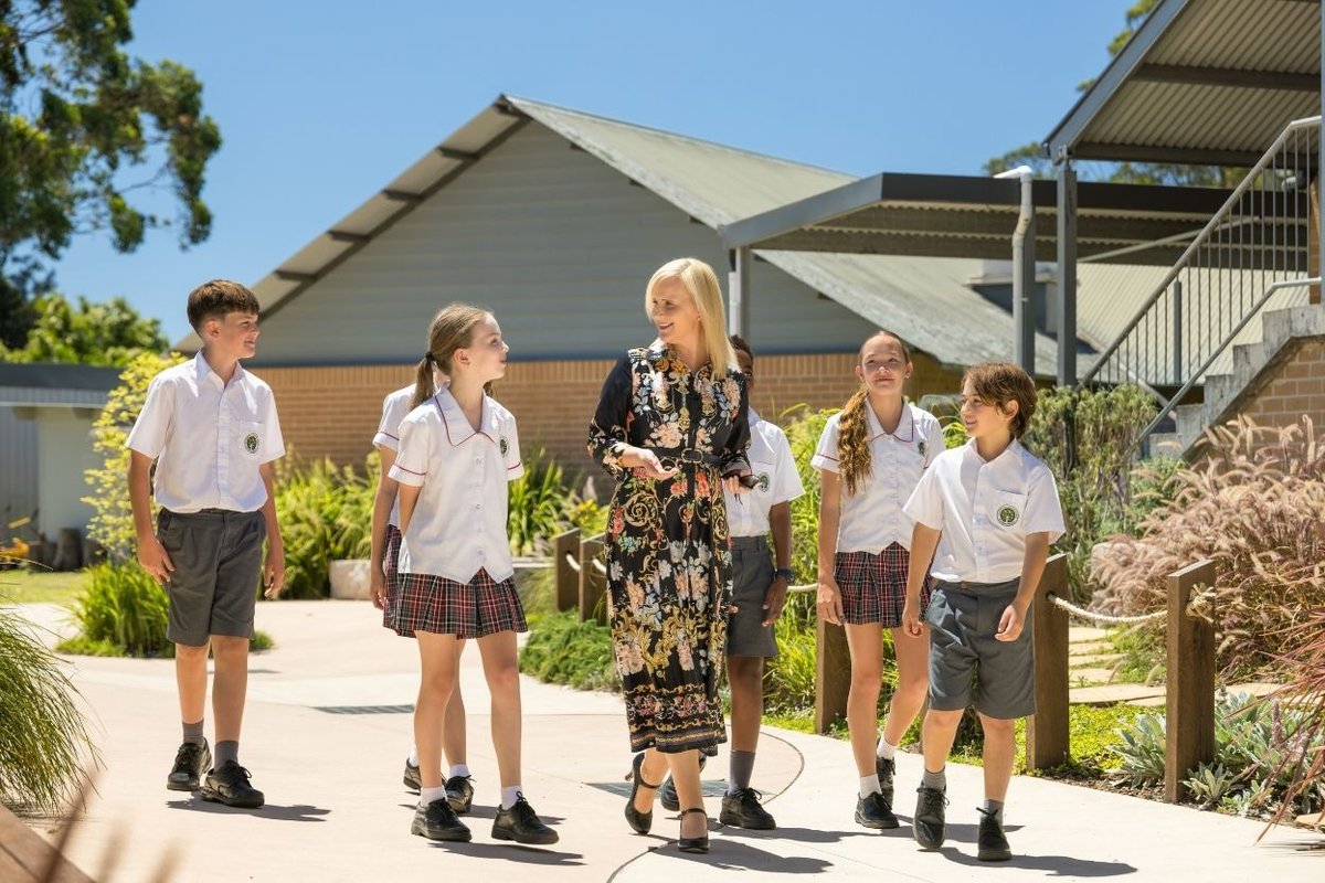 Students walking outdoors alongside a teacher.