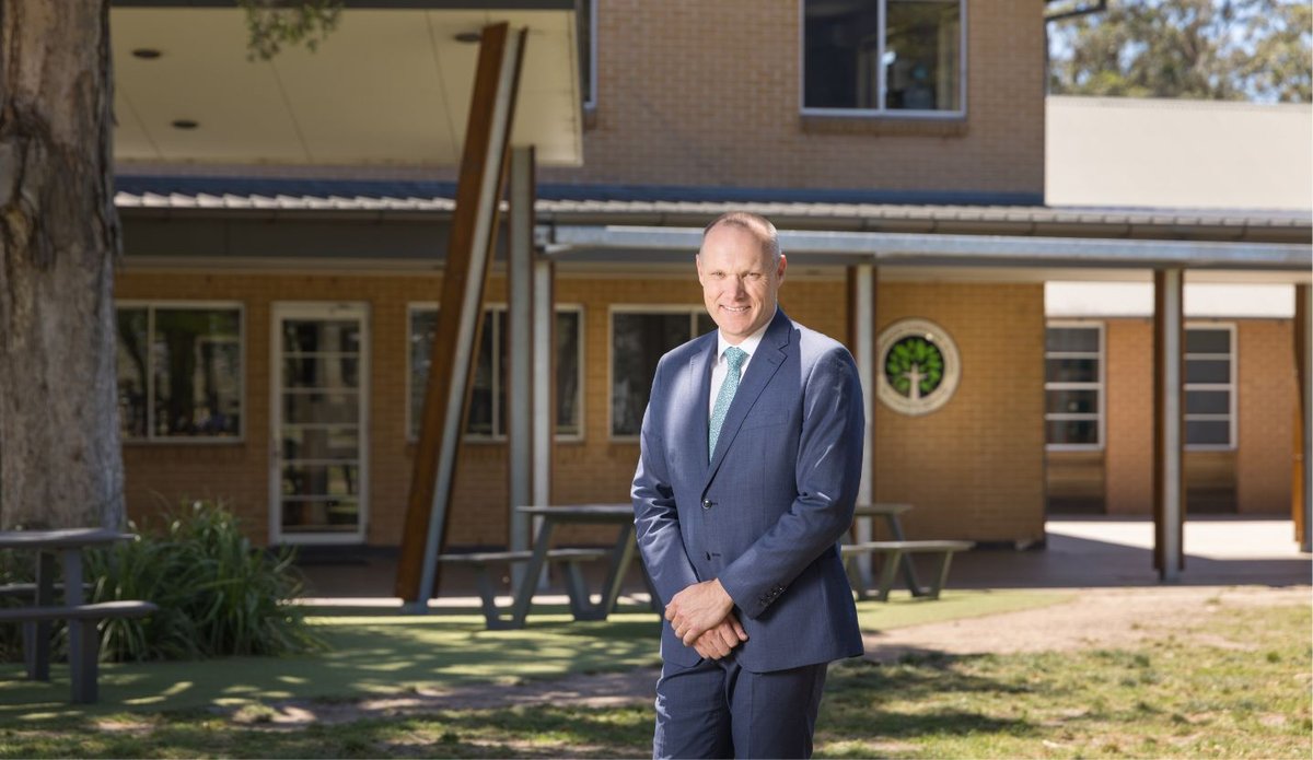 Principal Darren Hutton smiling while standing outdoors.