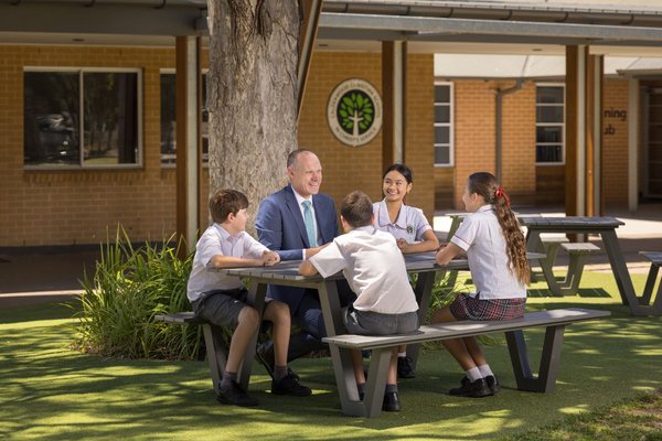 Principal Darren Hutton with Calderwood students at a table outdoors.